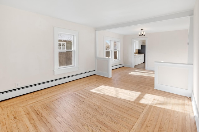 spare room featuring an inviting chandelier, a baseboard heating unit, and light wood-type flooring