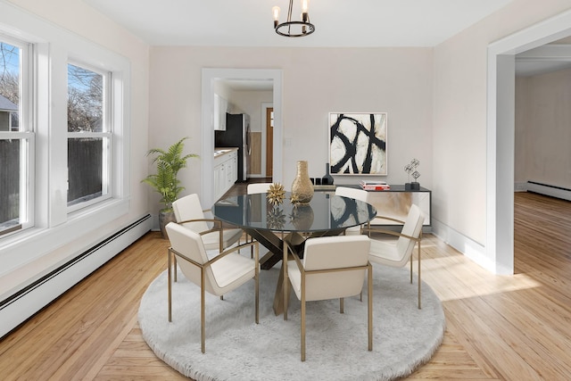 dining room with a baseboard radiator, light hardwood / wood-style flooring, and a notable chandelier