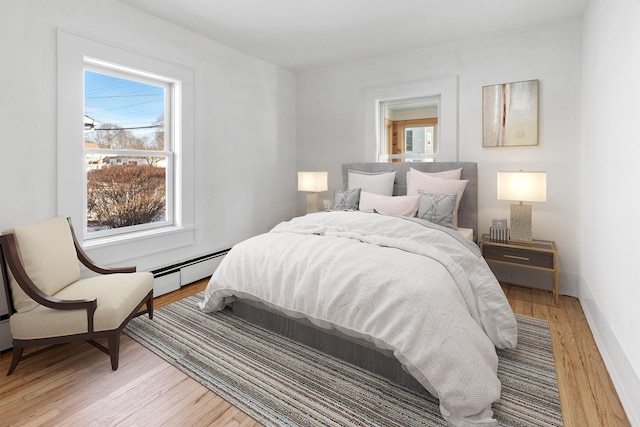 bedroom with baseboard heating and light wood-type flooring