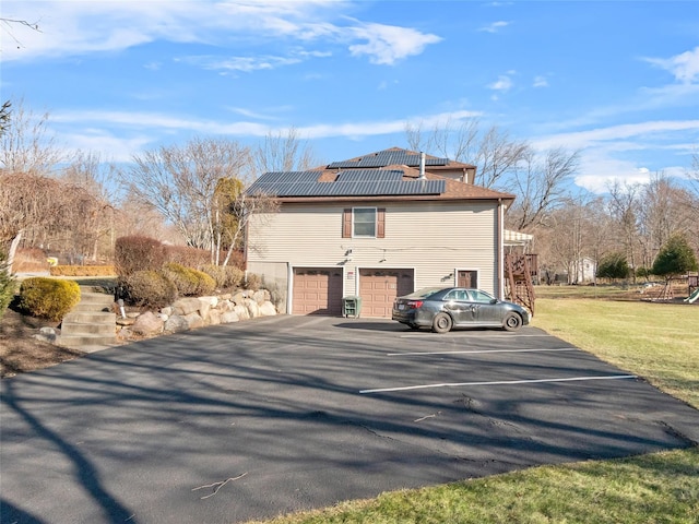 11 Balanchine Ct, Airmont, NY 10952 - view of property exterior with stairs, roof mounted solar panels, an attached garage, driveway, and a lawn