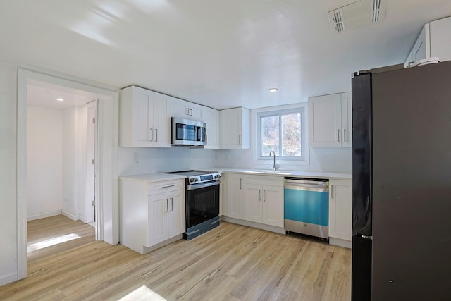 kitchen featuring light wood-type flooring, white cabinetry, sink, and appliances with stainless steel finishes