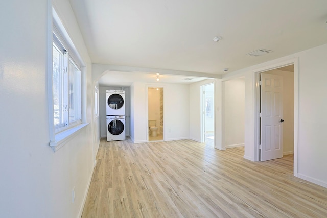 laundry area with light hardwood / wood-style flooring and stacked washer / dryer