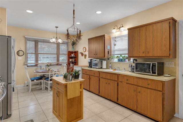 kitchen featuring a notable chandelier, a kitchen island, hanging light fixtures, appliances with stainless steel finishes, and light tile patterned floors