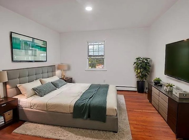 bedroom with hardwood / wood-style flooring and baseboard heating