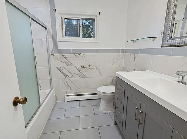 full bathroom featuring vanity, a baseboard heating unit, shower / bath combination with glass door, tile walls, and toilet