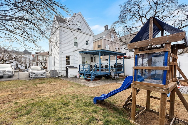 rear view of property with a playground, a wooden deck, a lawn, and central AC unit