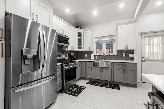 kitchen with gray cabinets, stainless steel appliances, vaulted ceiling, white cabinets, and sink