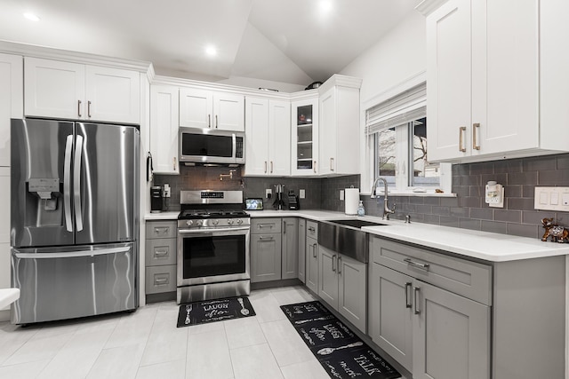 kitchen with lofted ceiling, white cabinetry, stainless steel appliances, sink, and gray cabinetry