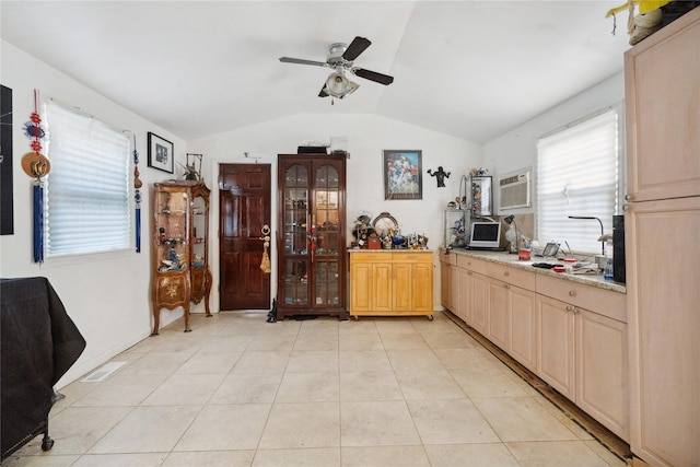 kitchen featuring light stone countertops, light brown cabinetry, ceiling fan, lofted ceiling, and light tile patterned flooring