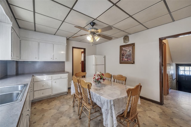 dining area featuring a drop ceiling, ceiling fan, and sink