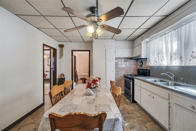 kitchen featuring gas stove, white cabinetry, sink, ceiling fan, and backsplash