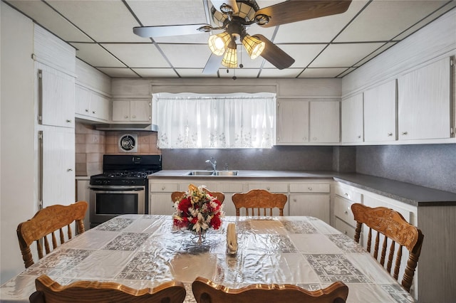 kitchen with gas range, ceiling fan, sink, a drop ceiling, and decorative backsplash