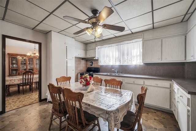 dining area with a paneled ceiling, ceiling fan with notable chandelier, and sink