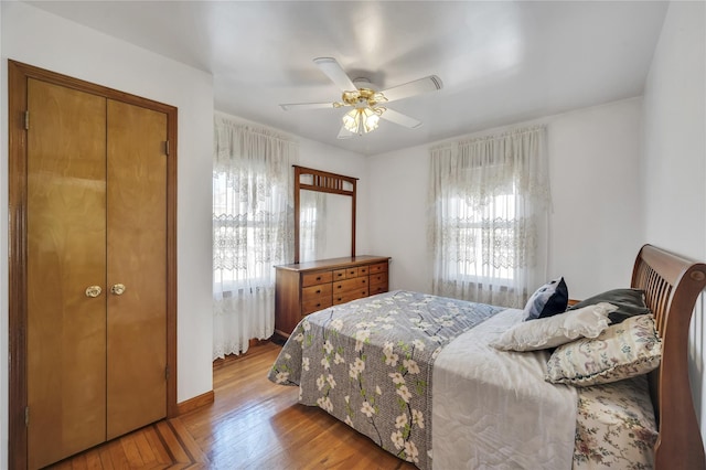 bedroom with ceiling fan, a closet, light wood-type flooring, and multiple windows