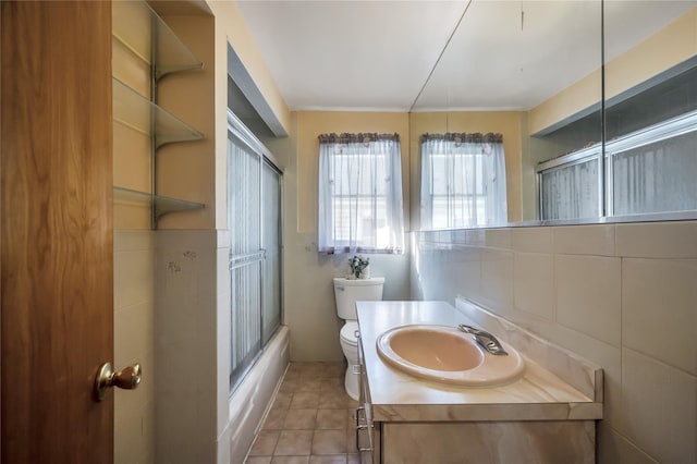 full bathroom with vanity, shower / bath combination with glass door, tile patterned flooring, toilet, and tile walls