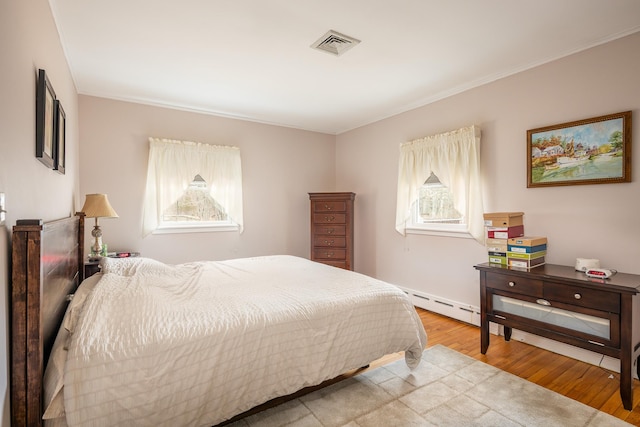 bedroom with baseboard heating and light hardwood / wood-style flooring