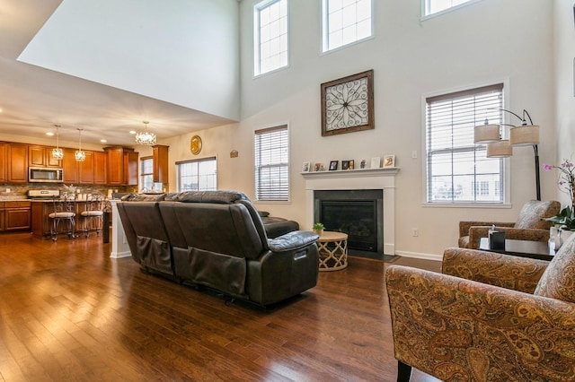 living room featuring a towering ceiling, dark hardwood / wood-style flooring, and a chandelier