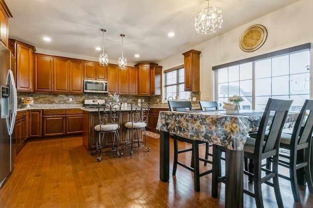 kitchen with a chandelier, stainless steel appliances, a breakfast bar, pendant lighting, and a kitchen island