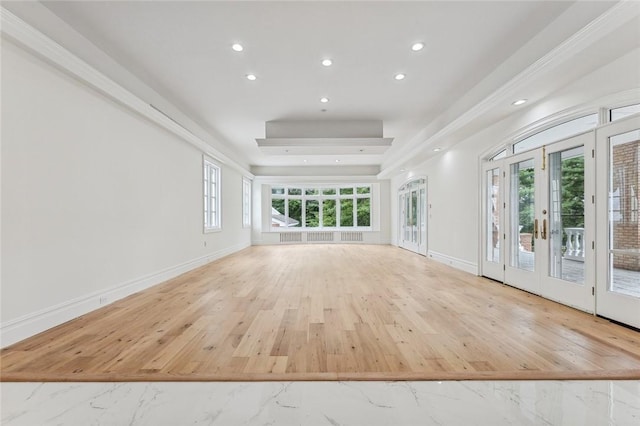 unfurnished living room with a tray ceiling and french doors