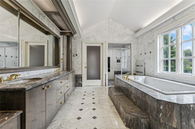 bathroom with vanity, tiled tub, and vaulted ceiling