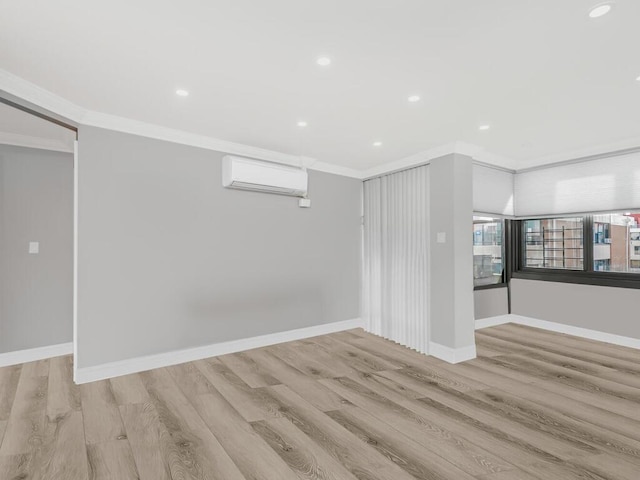 spare room with an AC wall unit, light wood-type flooring, and ornamental molding