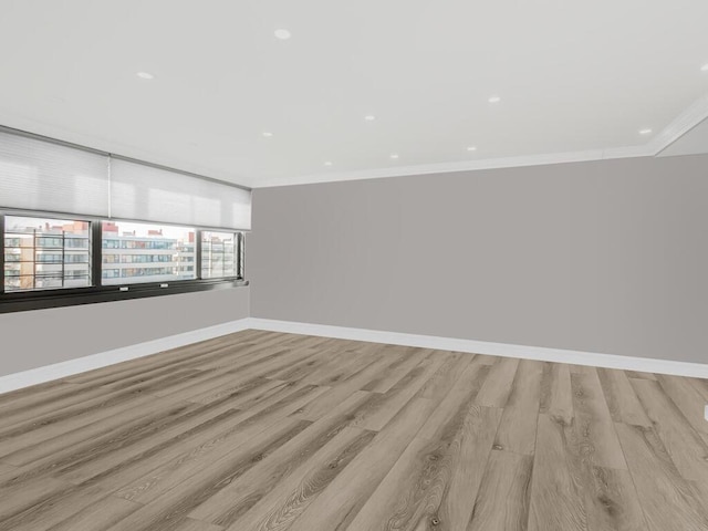 empty room featuring light wood-type flooring and ornamental molding