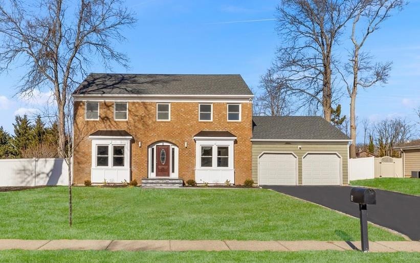 colonial-style house featuring a front lawn and a garage