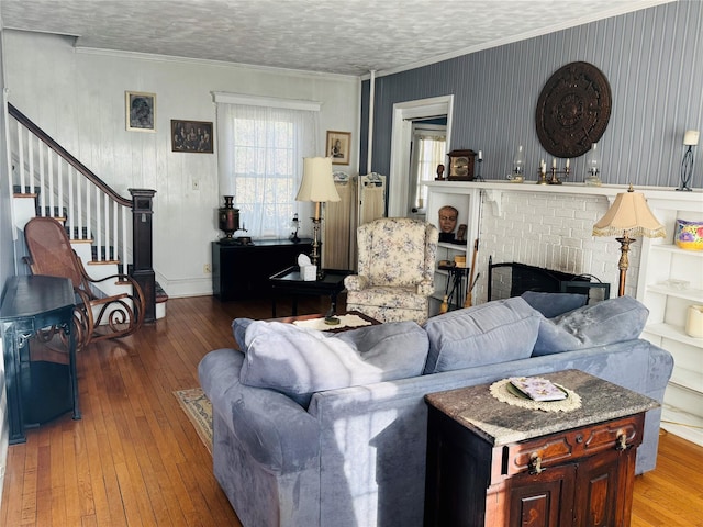 living room featuring a fireplace, a textured ceiling, hardwood / wood-style flooring, and crown molding