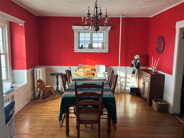 dining area featuring radiator heating unit, ornamental molding, a textured ceiling, a notable chandelier, and wood-type flooring