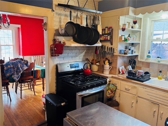 kitchen with gas stove, backsplash, sink, and light hardwood / wood-style flooring