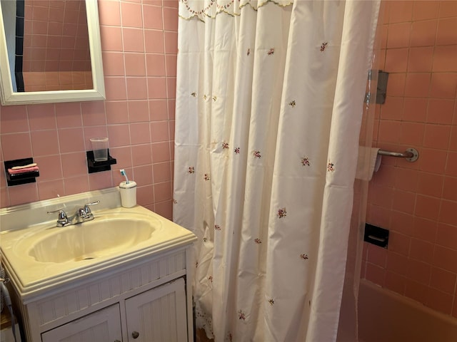 bathroom with shower / tub combo with curtain, vanity, and tile walls