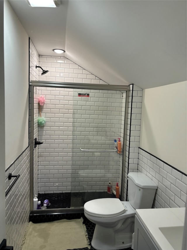 bathroom with lofted ceiling, toilet, a shower with door, vanity, and tile walls