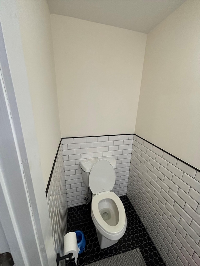 bathroom featuring toilet and tile walls