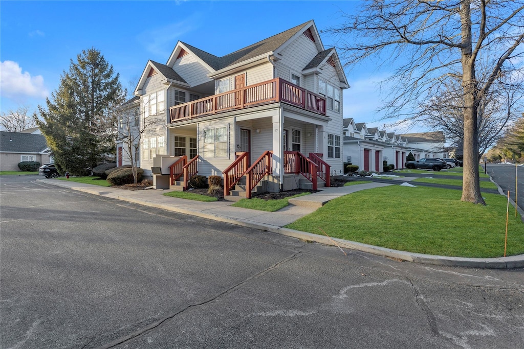 view of front of home with a balcony and a front lawn