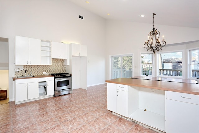 kitchen with pendant lighting, high vaulted ceiling, white cabinets, and stainless steel range