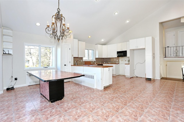 kitchen featuring high vaulted ceiling, decorative light fixtures, a kitchen island, white cabinetry, and a chandelier