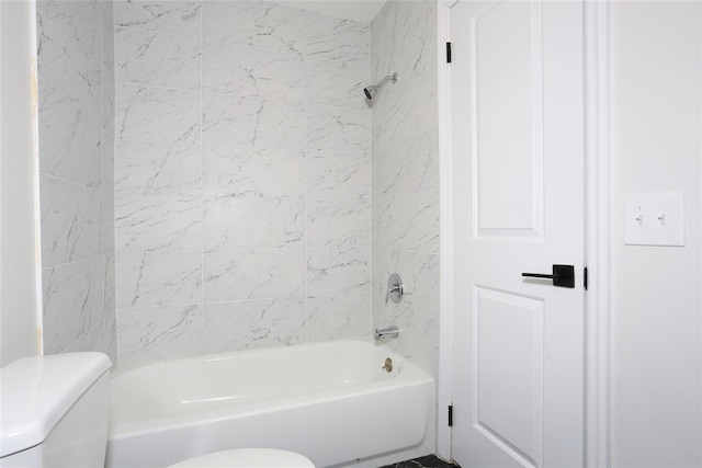 bathroom featuring tiled shower / bath combo and toilet