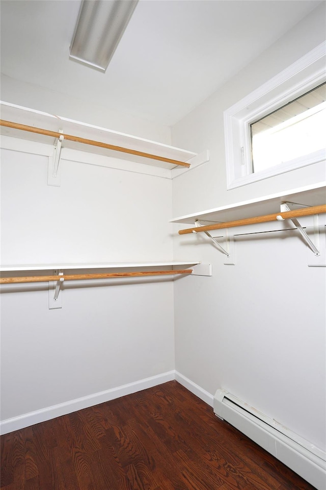 walk in closet with dark hardwood / wood-style flooring and a baseboard heating unit