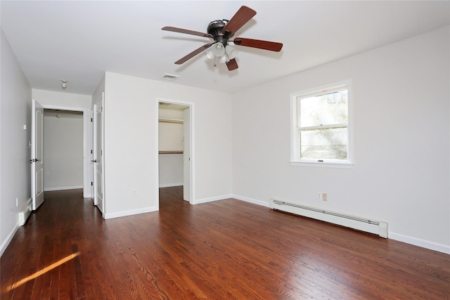 unfurnished bedroom featuring dark wood-type flooring, a baseboard heating unit, ceiling fan, a spacious closet, and a closet