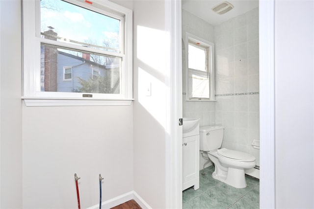 bathroom featuring a wealth of natural light, a baseboard radiator, toilet, and tile walls