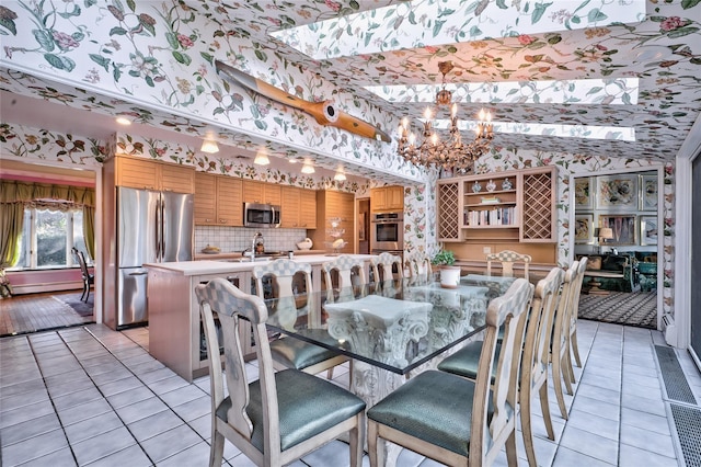 dining space featuring baseboard heating, sink, a chandelier, and light tile patterned flooring