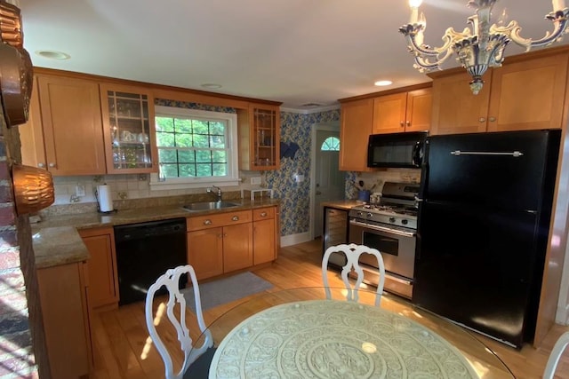 kitchen with sink, light hardwood / wood-style flooring, a notable chandelier, light stone countertops, and black appliances