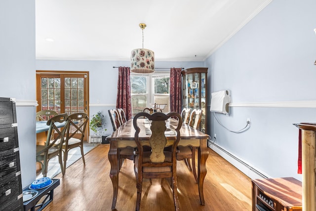 dining space featuring wood-type flooring, plenty of natural light, a baseboard heating unit, and crown molding