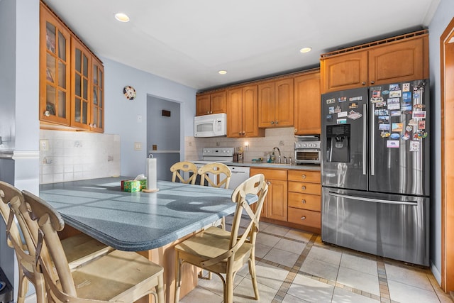 kitchen with sink, decorative backsplash, light tile patterned floors, and stainless steel refrigerator with ice dispenser