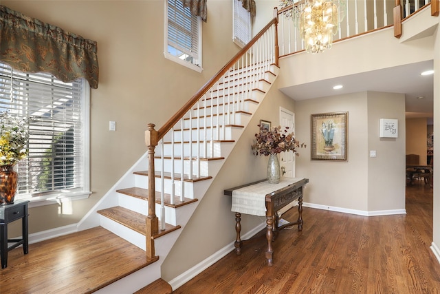 stairs featuring a high ceiling, an inviting chandelier, and wood-type flooring