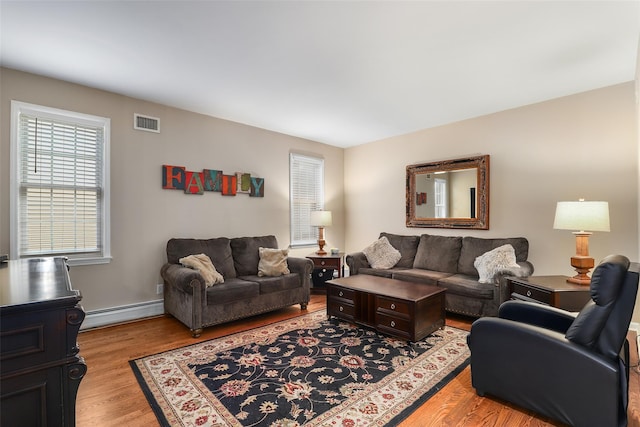 living room featuring a baseboard heating unit and light hardwood / wood-style floors