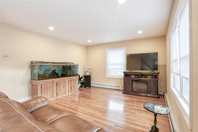 living room with light wood-type flooring, a fireplace, and a baseboard radiator