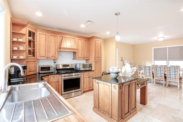 kitchen featuring dark stone countertops, a center island, custom exhaust hood, hanging light fixtures, and appliances with stainless steel finishes