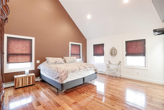 bedroom with light wood-type flooring, multiple windows, and a baseboard radiator