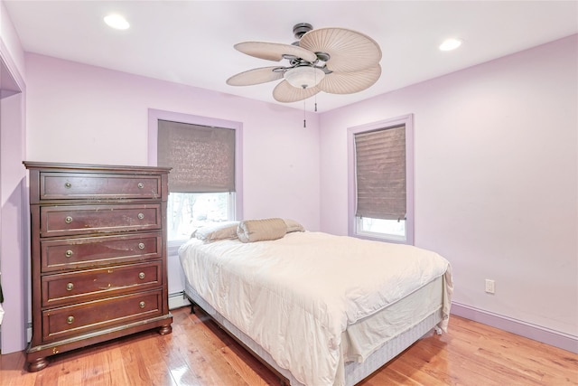 bedroom with a baseboard heating unit, ceiling fan, and light hardwood / wood-style flooring